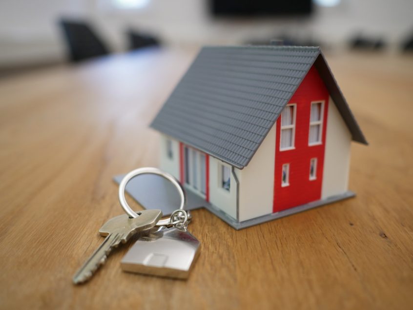 A First Time Homebuyers keychain on a table next to a toy house